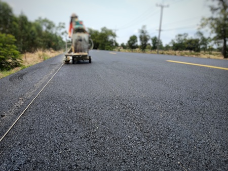 Technicians are working on white traffic lines on the asphalt surface.の写真素材