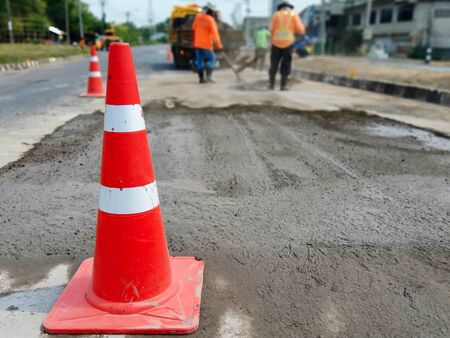 Motion blur, road construction with a red rubber cone in frontの写真素材