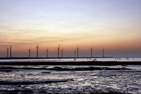 beautiful sunset in Taiwan with wind power generator at a wetlandの写真素材