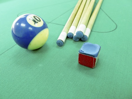 Close-up billiard balls and cue stick with chalk block on table indoorsの写真素材