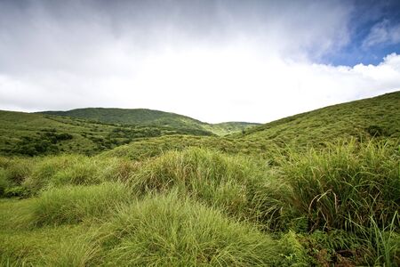 Grass Mountain and blue cloudy sky background located in Taipei, Taiwanの写真素材