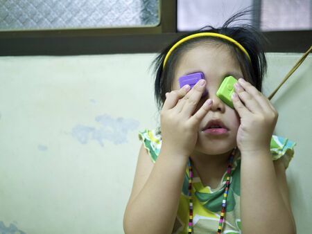 Close-up portrait of a beautiful cute girl with toys cover eyes,wry faceの写真素材