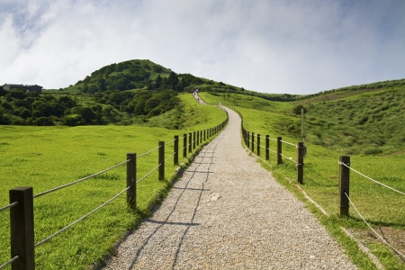 gravel path in green mountain against blue cloudy skyの写真素材