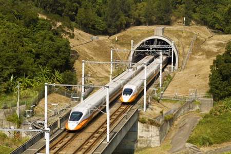 high speed commuter train driving across tunnel with mountain sceneryのeditorial素材