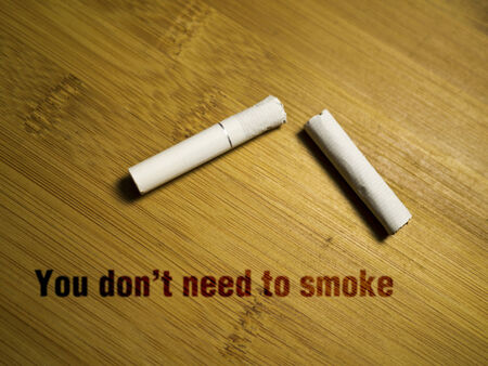 broken cigarette on wooden background with textの写真素材