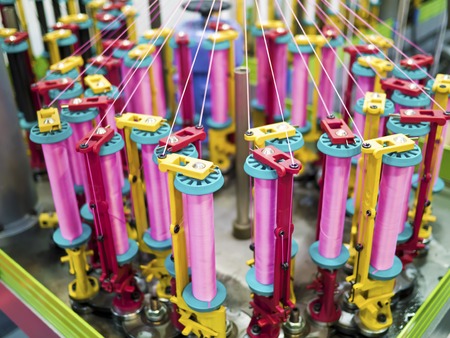 Textile industry - yarn spools on spinning machine in a textile factoryの写真素材