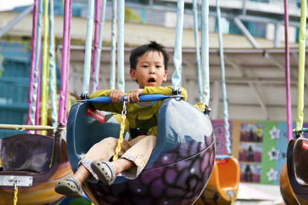 Taipei, Taiwan - SEP 30, 2015: happy young child on the chain swing carousel in The Taipei Children's Amusement Parkのeditorial素材