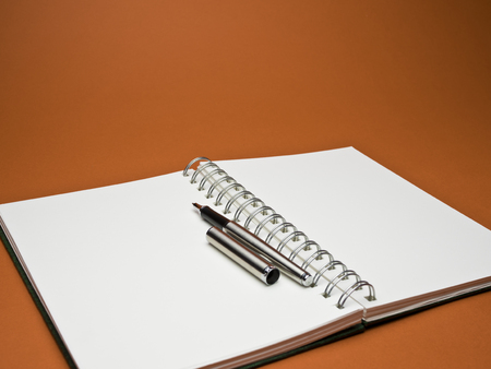 white sketchbook with silver metallic ball point pen on red backgroundの写真素材