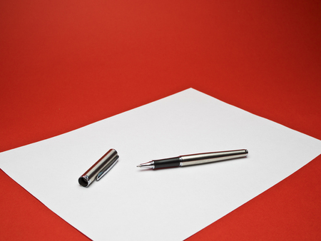 ball point silver pen on white paper with red backgroundの写真素材