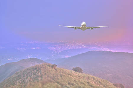 perspective view of jet airliner in flight above mountains and fog and night cityのeditorial素材