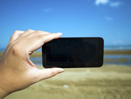 smart phone on hand at summer beachの写真素材