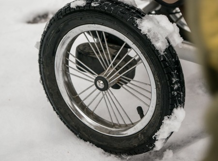 Wheel of the baby carriage stroller with snow in winterの写真素材