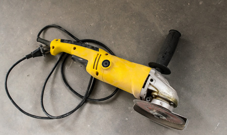 Dirty yellow angle grinder on a gray concreteの写真素材