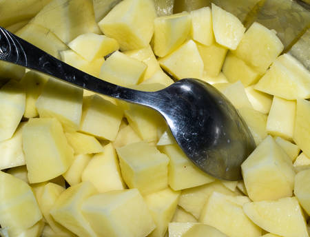 Cut raw fresh potatoes and spoon in a metal saucepanの写真素材