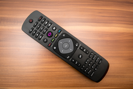 TV remote control black gray on the brown tableの写真素材