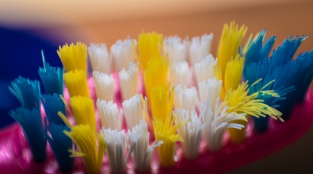Old toothbrush macro with yellow, blue and white bristlesの写真素材