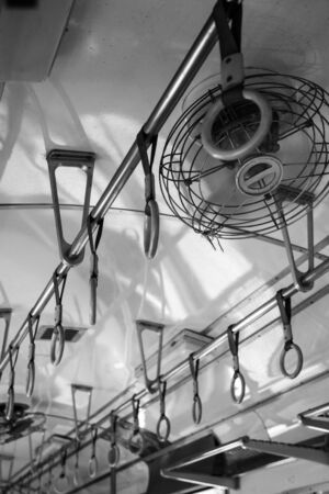 Travelling on your own trough asia - Handles and ventilator on ceiling for standing passenger inside a train Thailand. Picture taken in black and white - vintage lookの写真素材
