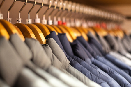 A new collection of cloths hanging on hangers in the store shopの写真素材