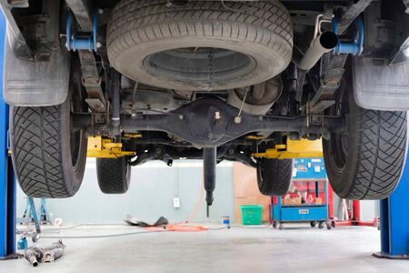 a car is on a lifting platform for repair in car service center shopの写真素材
