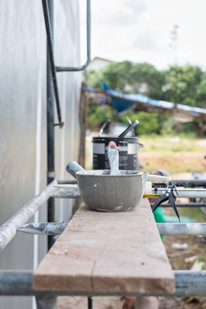 Paint cans and equipment on scaffolding for painting the wall in construction. Construction tool paint.の写真素材