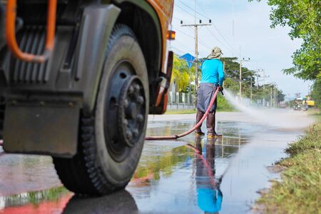 a worker spraying water to clean the road with pressurized water system, wet cleaning of street.の写真素材