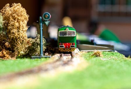a miniature green train stopped at the red light. Front view, with rails and grassの写真素材