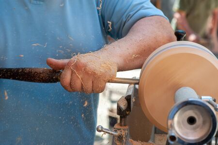 the man works on the lathe with a piece of wood and a chisel. Shavings rise in the airの写真素材