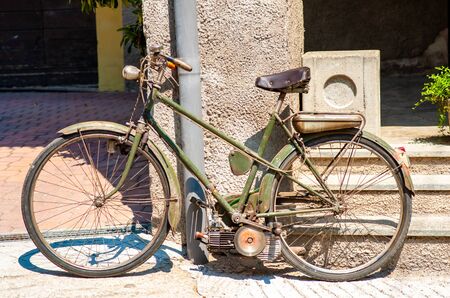 a vintage green bicycle with engine, leaning against the wallの写真素材