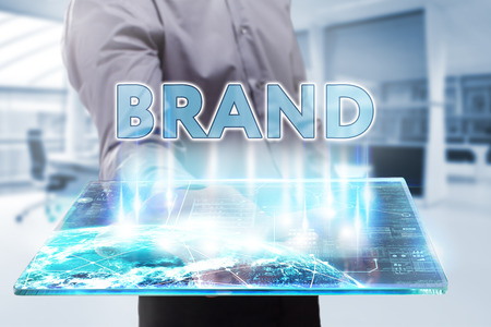 Business, Technology, Internet and network concept. Young businessman working on a tablet of the future, he sees the inscription: brandの写真素材