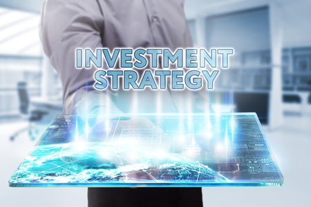 Business, Technology, Internet and network concept. Young businessman working on a tablet of the future, he sees the inscription: investment strategyの写真素材
