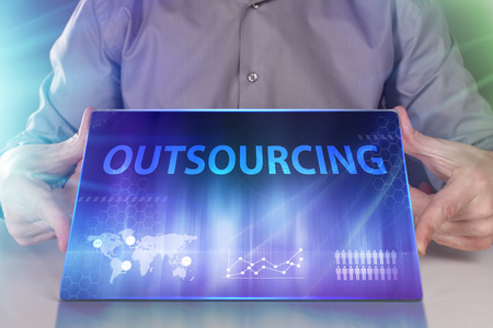 The concept of business, technology, the Internet and the network. A young entrepreneur working on a virtual screen of the future and sees the inscription: Outsourcingの写真素材