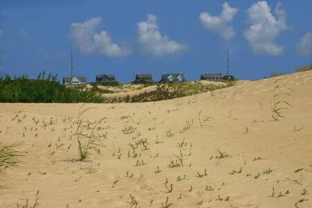 Rooftops of seaside homes peak up from sand dunesの写真素材