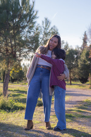 Young daughter points to something in the distance while her mother looks on with a surprised expression both embracing each other in a peaceful autumn park. This image captures the deep bond curiosity and joy that defines their relationship.の写真素材