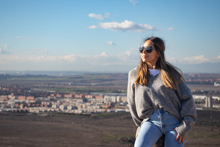Young woman sitting on a hill wearing sunglassesの写真素材