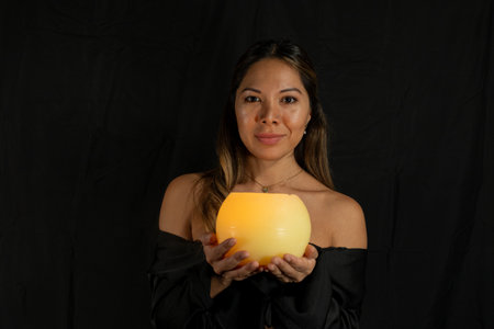 latina woman, with brown and golden hair and brown skin posing and looking at the camera with black background.の写真素材