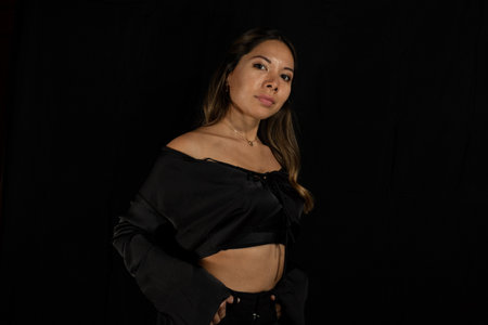 posing beautiful latina woman, with brown and golden hair and brown skin posing and looking at the camera with black background.の写真素材