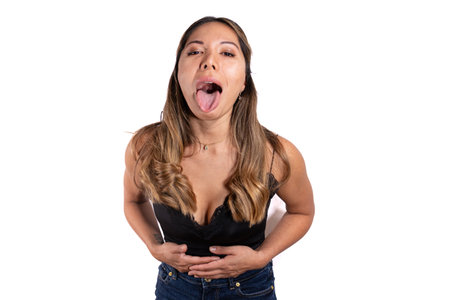 beautiful latina woman with brown and golden hair and tanned skin posing and looking at the camera with white background black top and jeansの写真素材