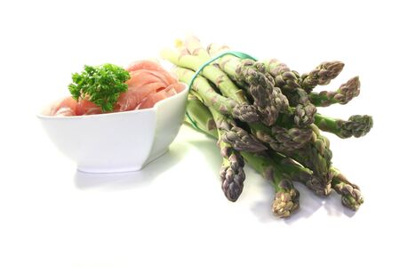 a bundle of green asparagus with ham on a white backgroundの写真素材