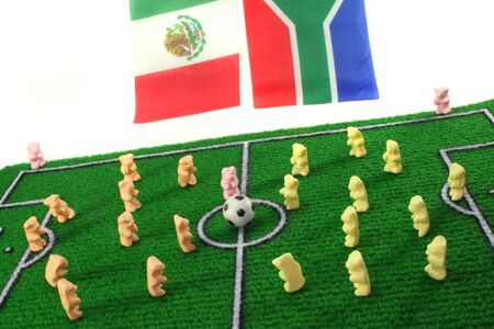 Gummi Bears play football on a soccer field before a white background