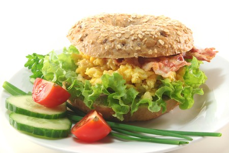 Rye bagel with salad, scrambled eggs and baconの写真素材