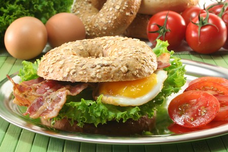 Rye bagel with salad, fried egg and baconの写真素材
