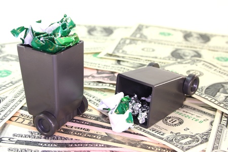 full garbage cans with dollar bills before a white background