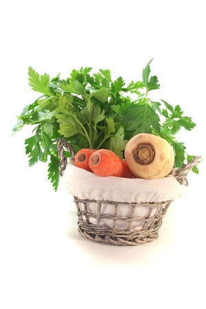 Greens with kohlrabi, carrots, leek, parsley and parsley root in the basketの写真素材