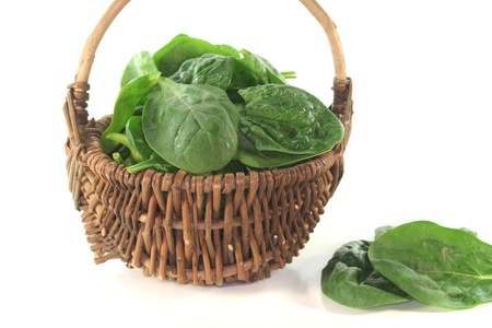 fresh green spinach leaves in a basket on white backgroundの写真素材