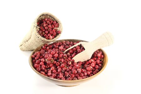 red peppercorns in a bowl with sack and bushels on a white backgroundの写真素材