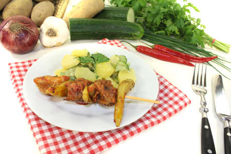 Potato-cucumber salad with fire skewers and parsley on a light の写真素材