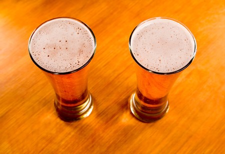 Two beer glasses on wooden table, soft focus  の写真素材