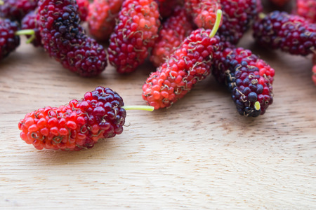 A group of fresh mulberries laid on a wooden floor.の写真素材