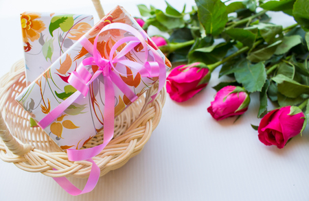 Pink roses and gift boxes on a basket on a white background.の写真素材