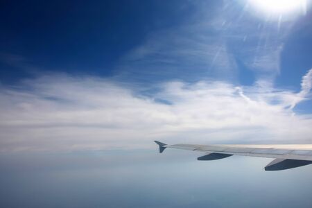 	Aircraft wing in the sky  	View from the plain on white clouds and space above the cloudsの写真素材
